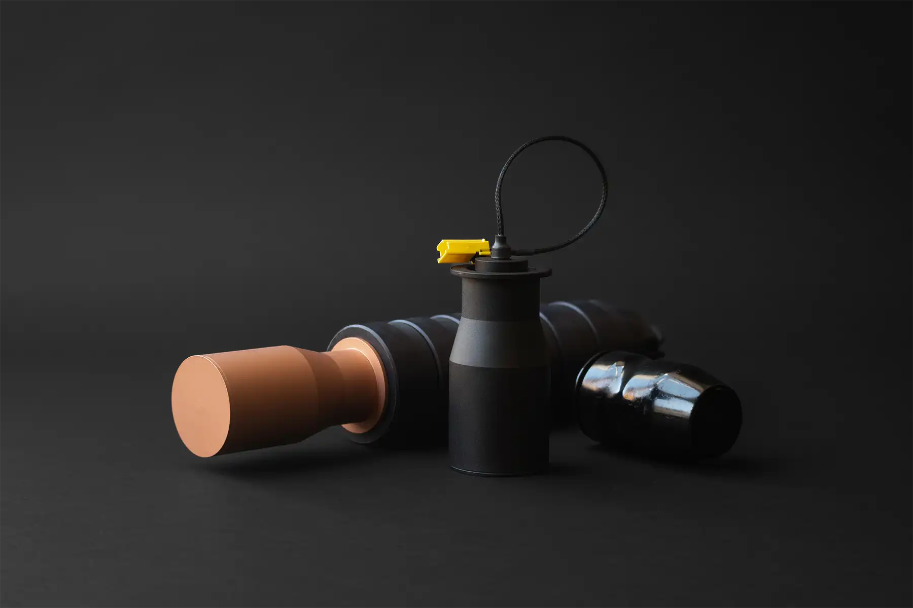 Drone warheads with modular black bodies and yellow safety plugs on dark background